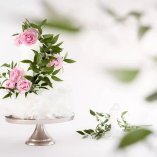 Tort pietrowy weganski na wesele ozdobiony kwiatami z oplatka waflowego o raz liscmi rafii